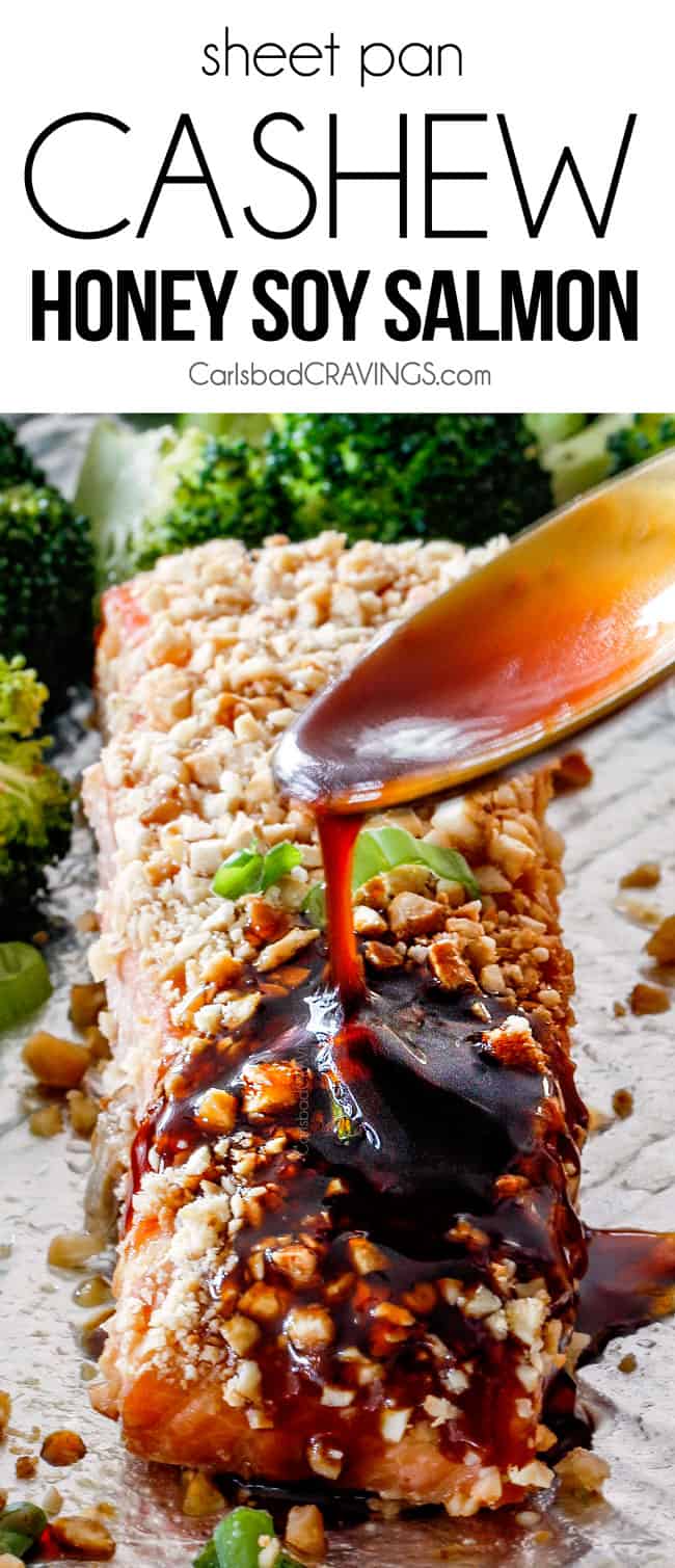 This Sheet Pan Cashew Honey Soy Salmon looks impressive but is SO easy and cray delicious!! It's tender and juicy on the outside, crusted in crunchy, buttery, roasted cashews on the outside, and drizzled with to-live-for Honey Soy Glaze all over! front up close view of spoon honey soy sauce over a fillet of honey soy salmon