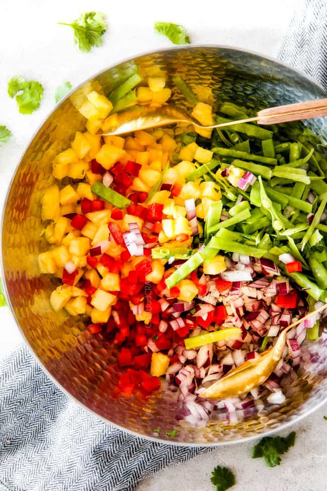 pineapple snow pea salsa in a silver bowl with gold tongss