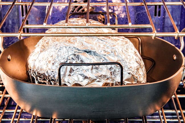 Showing How to Cook a Precooked Ham by placing foil covered ham in roasting pan on a roasting rack
