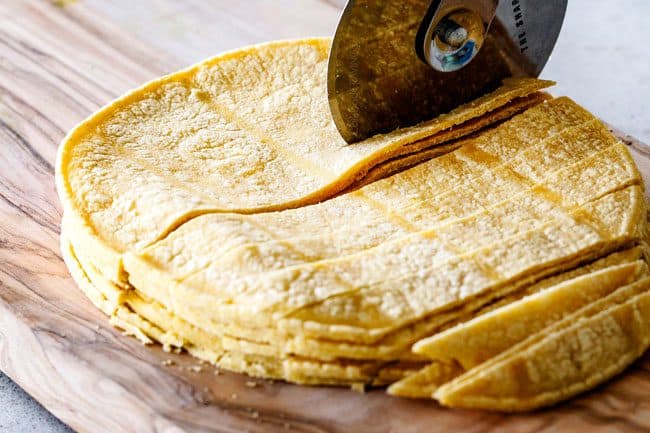 showing how to make Mexican Salad by by cutting corn tortillas to make tortilla strips on a cutting board with a pizza cutter