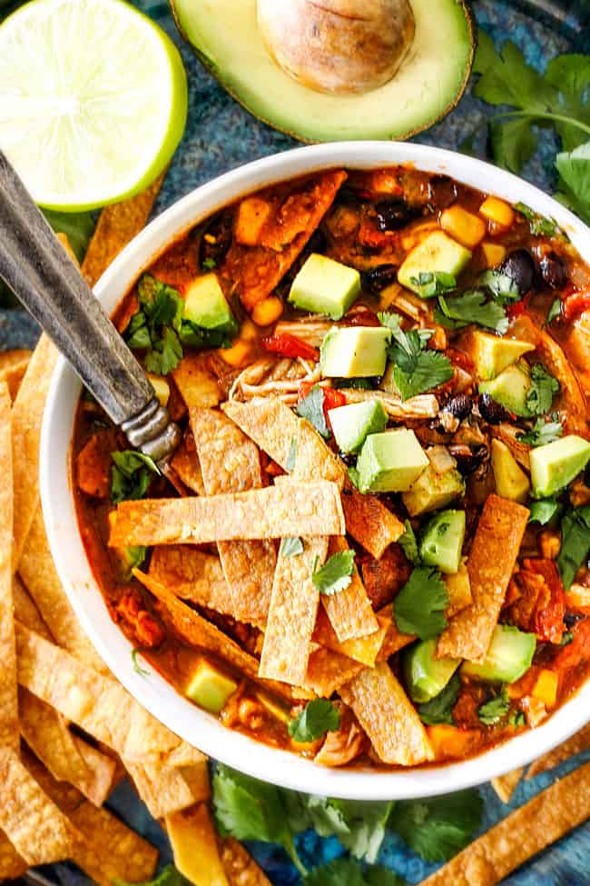 Easy 30-Minute Homemade Chicken Tortilla Soup that tastes better than any restaurant! It's accidentally healthy, easy to double/triple for a crowd, freezer friendly and tastes like it's been simmering for hours but on your table in 30 Minutes! a white bowl of Mexican Chicken Tortilla Soup loaded homemade tortilla strips, avocados, sour dream