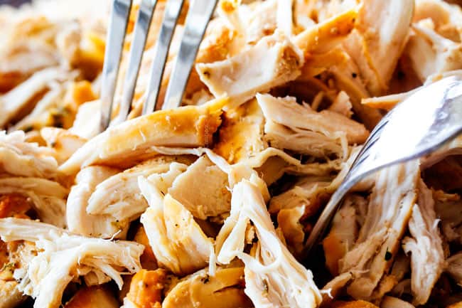 showing how to make creamy chicken noodle soup recipe by shredding chicken on a cutting board