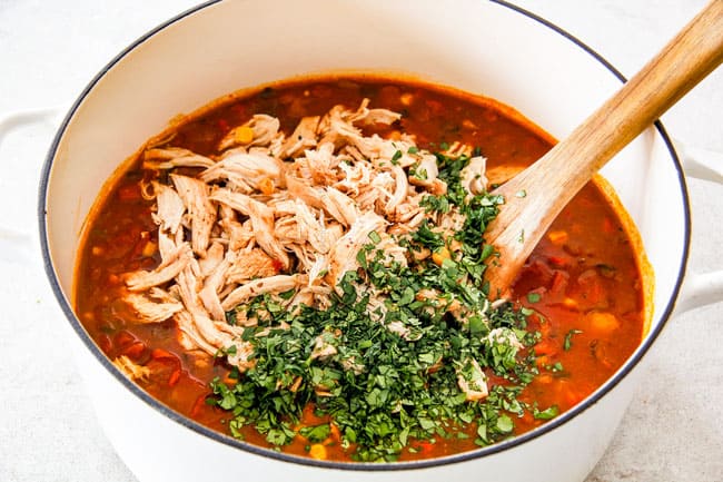 Easy 30-Minute Homemade Chicken Tortilla Soup that tastes better than any restaurant! It's accidentally healthy, easy to double/triple for a crowd, freezer friendly and tastes like it's been simmering for hours but on your table in 30 Minutes! Showing How to Make Chicken Tortilla Soup by adding shredded chicken, cilantro and lime juice to Dutch oven