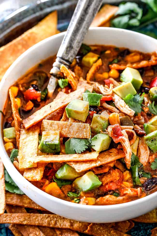 Easy 30-Minute Homemade Chicken Tortilla Soup that tastes better than any restaurant! It's accidentally healthy, easy to double/triple for a crowd, freezer friendly and tastes like it's been simmering for hours but on your table in 30 Minutes! Up close of a spoonful of best chicken tortilla soup loaded with avocados, tortilla strips, black beans and corn
