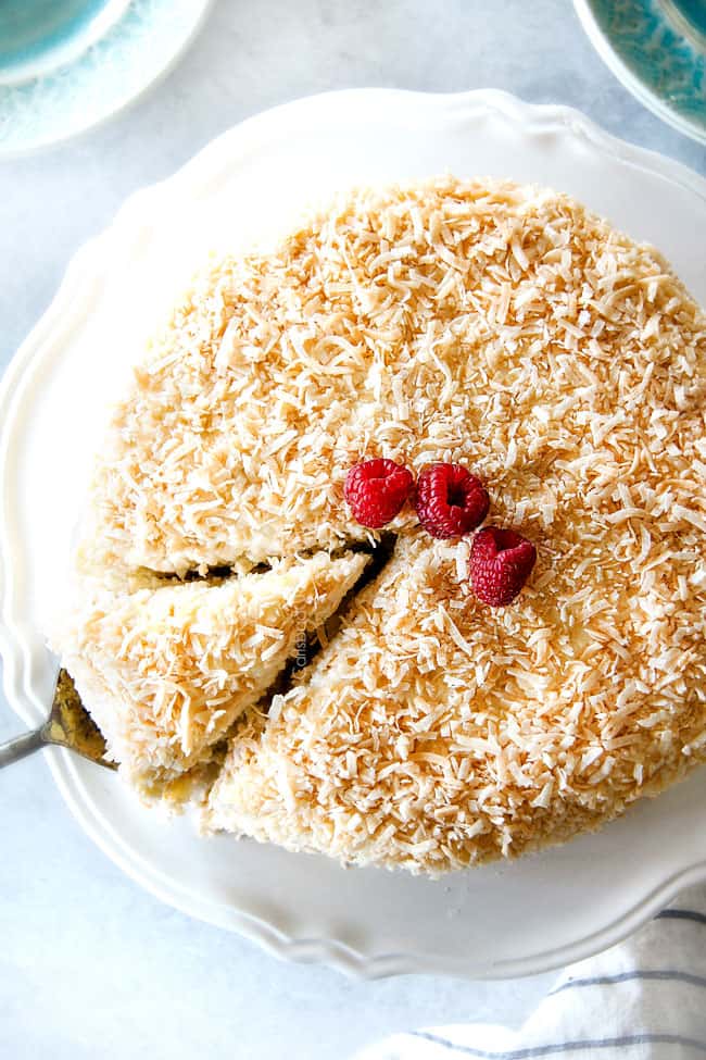 Top view of Coconut Cream Cake on a white cake stand with one piece cut out