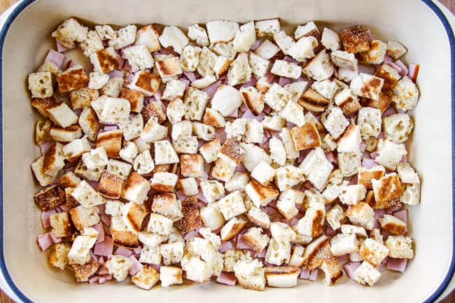 Showing how to make Eggs Benedict Casserole by layering cut up English muffins on top of Canadian Bacon in blue casserole dish