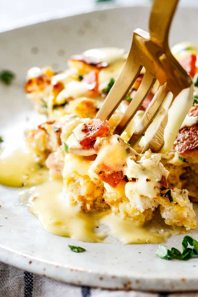 Up close shot of easy Eggs Benedict Casserole on a speckled plate with a fork taking a bite