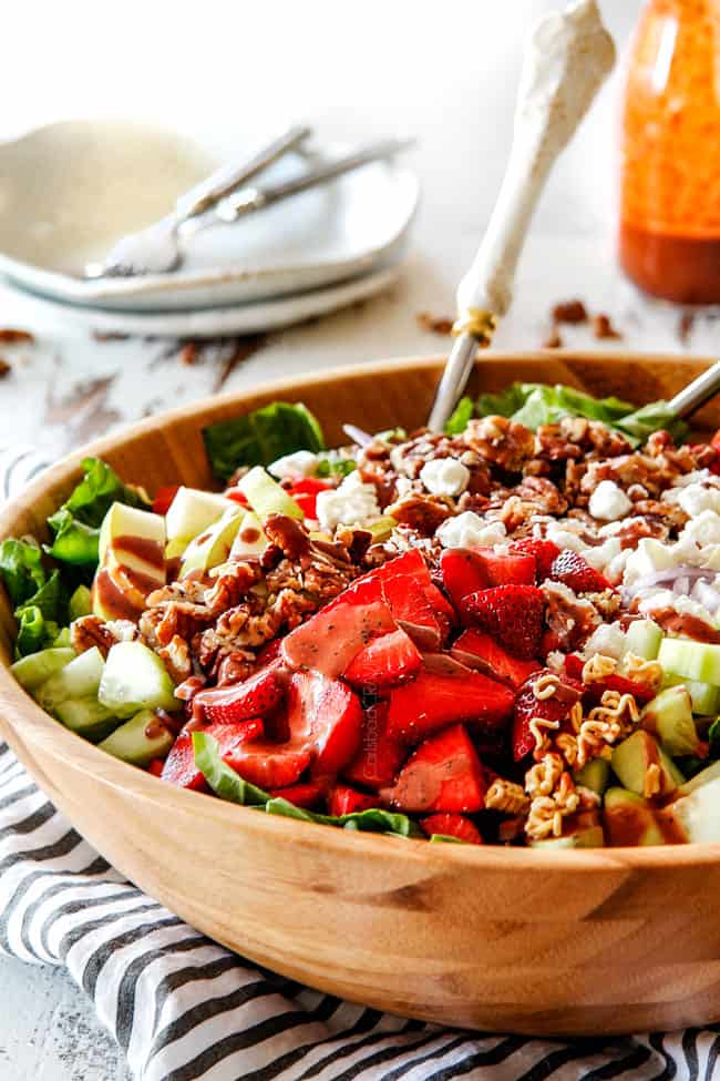 Side shot of best strawberry salad with Balsamic dressing in a wood bowl with white tongs
