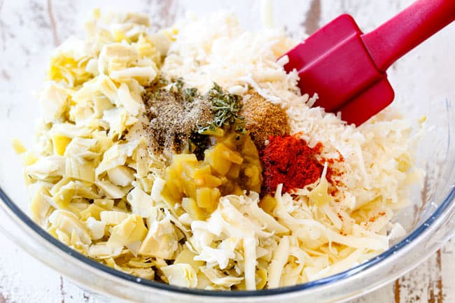 Showing how to make Artichoke Dip by mixing artichokes, Parmesan, mozzarella, sour cream and mayonnaise together in a glass bowl