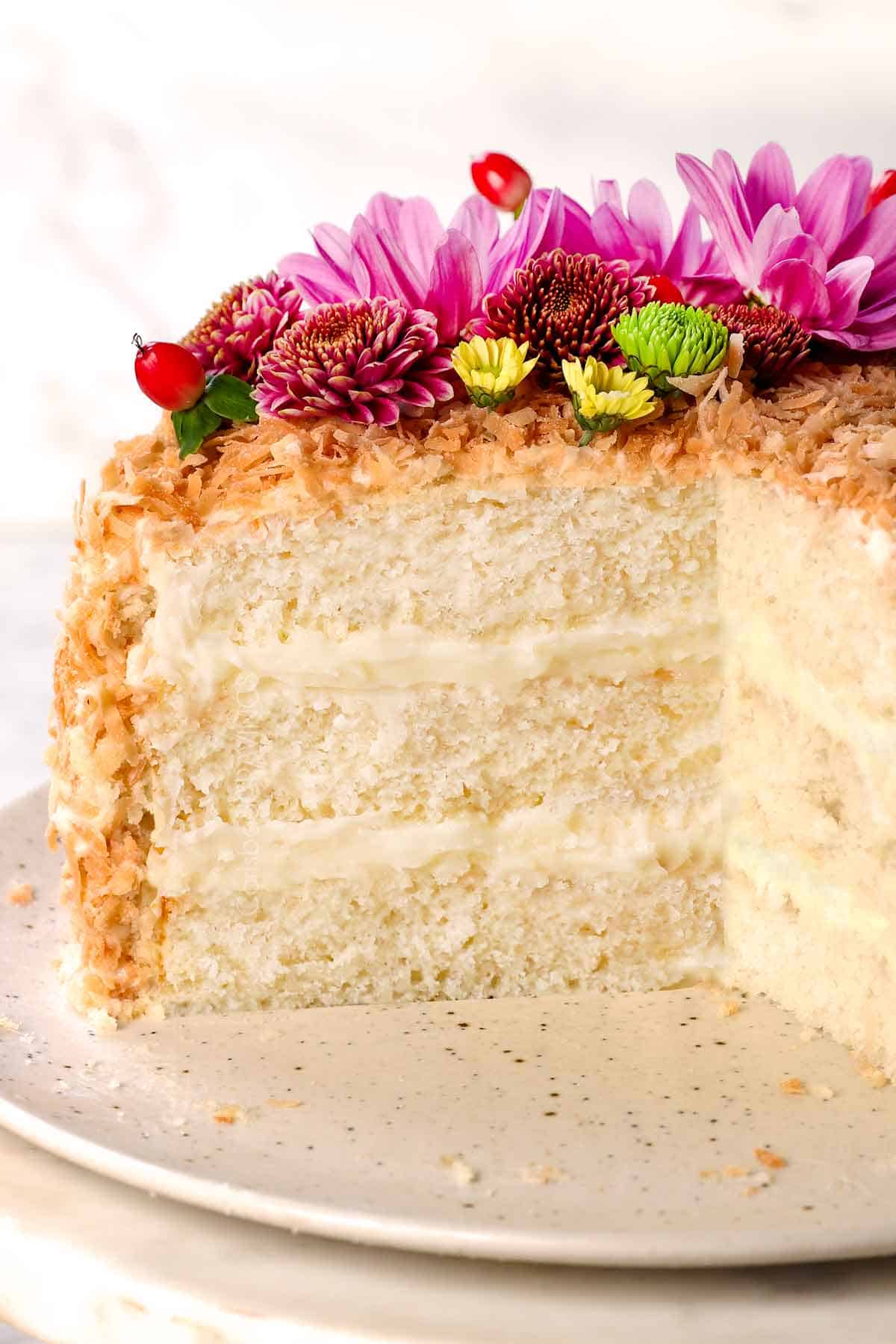 showing how to make coconut cake by frosting the outsides and pressing in toasted shredded coconut