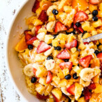 top view of easy Pina Colada Fruit Salad with pineapple, coconut, mandarin oranges, strawberries and blueberries in a white bowl