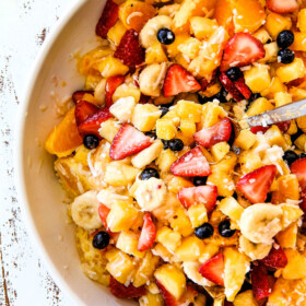 top view of easy Pina Colada Fruit Salad with pineapple, coconut, mandarin oranges, strawberries and blueberries in a white bowl
