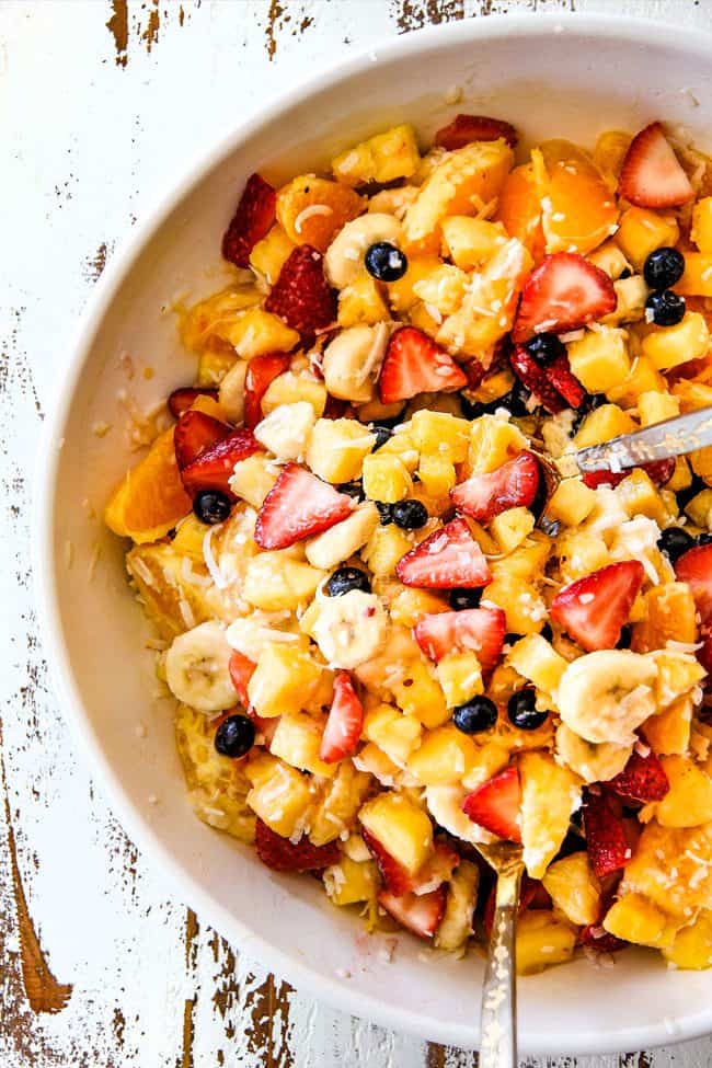 top view of easy Pina Colada Fruit Salad with pineapple, coconut, mandarin oranges, strawberries and blueberries in a white bowl