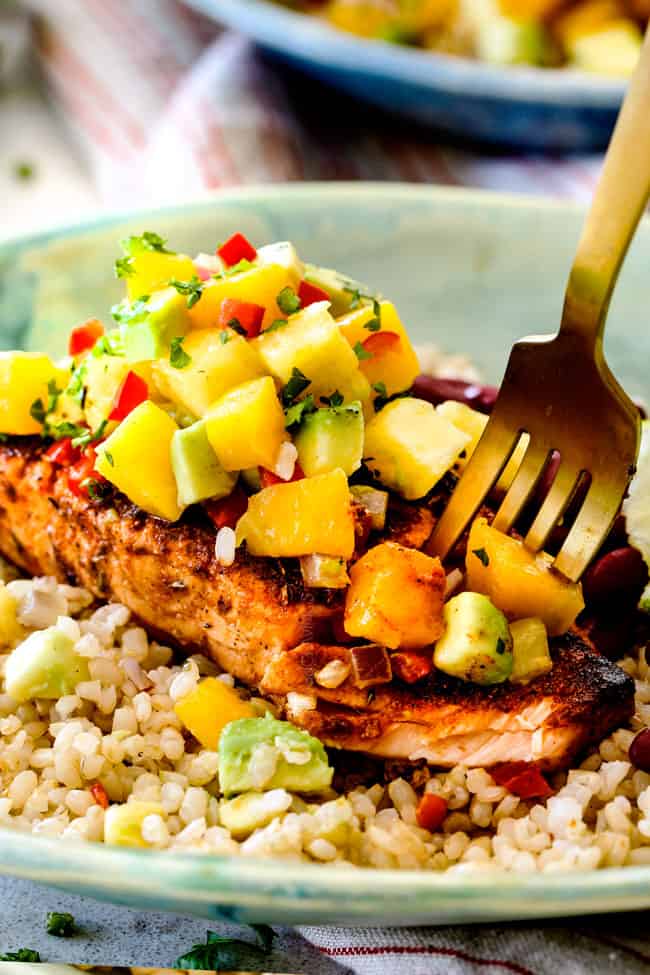 a golden fork taking a bite out of pan seared cajun salmon