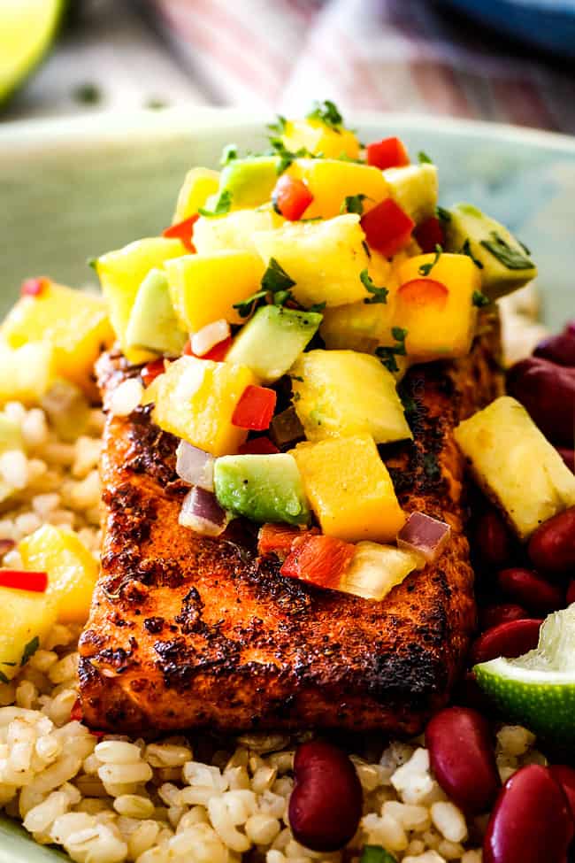 close up of pan seared cajun salmon in a green bowl with Pineapple, mango and rice