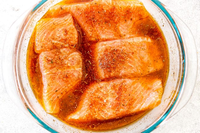 Cajun salmon marinating in a glass bowl with orange juice, lime juice and soy sauce