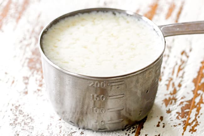 showing how to make homemade buttermilk by adding milk and vinegar to a measuring cup for moist Chocolate Raspberry Cake
