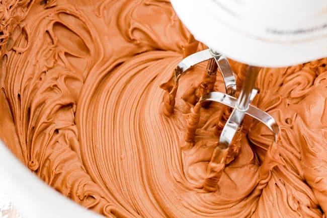 beating together chocolate ganache and mascarpone in a metal bowl for moist Dark Chocolate Raspberry Cake