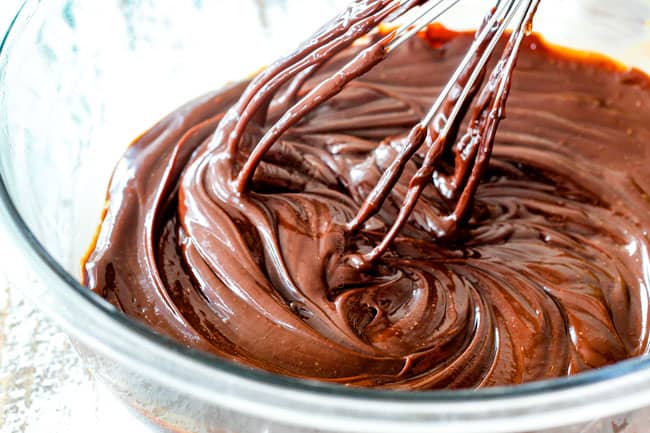 5 Minute Fool Proof Chocolate Ganache (sauce) is silky, creamy, sweet and 1,000 TIMES BETTER than any store bought chocolate sauce. Perfect for brownies, ice cream, cakes, popcorn, strawberries, etc whisking ganache in a glass bowl for Dark Chocolate Cake