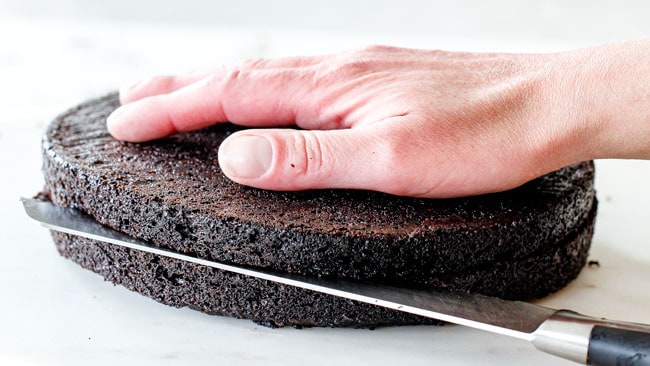 slicing moist Dark Chocolate Raspberry Cake in half to create layers