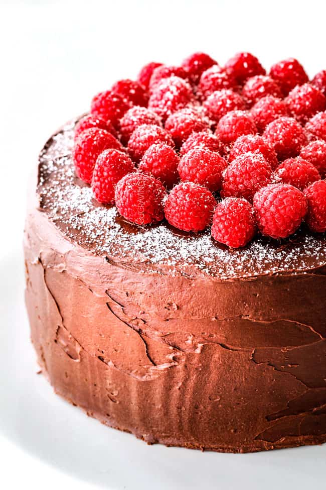 up close of easy Chocolate Raspberry Cake on a white pedestal with raspberries on top