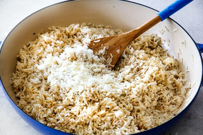 Showing how to prepare Lemon Rice by adding feta to cooked lemon rice in a blue skillet