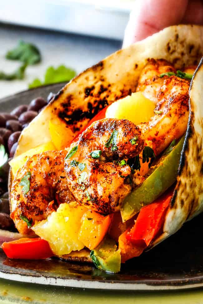 up close of oven roasted shrimp fajitas on a metal plate with bell peppers, onions and pineapple