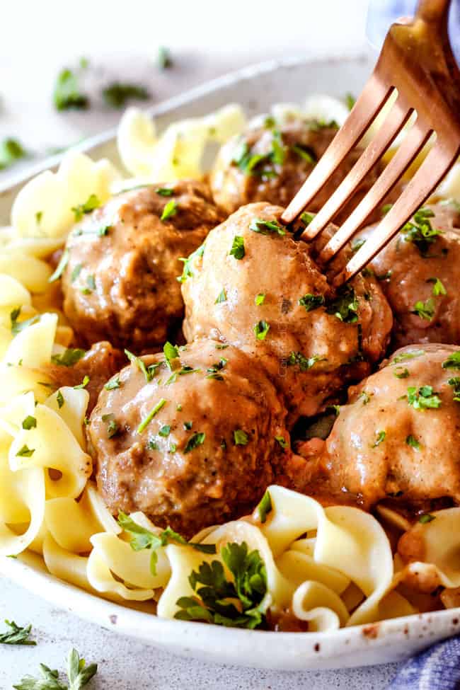 Swedish Meatballs with egg noodles on a plate with a fork sticking into a meatballs