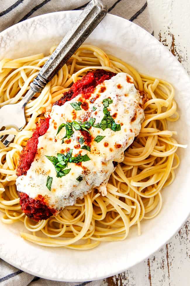 top view of a single piece of Chicken Parmesan on a bed of spaghetti on a white plate