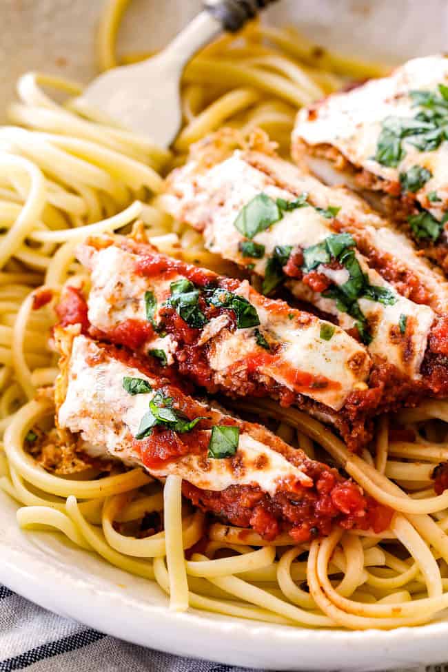 up close of view of slices of baked chicken Parmesan with mozzarella cheese, Parmesan and fresh basil.