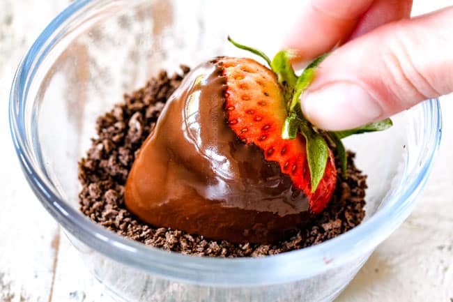 rolling chocolate covered strawberry in crushed chocolate graham cracker crumbs