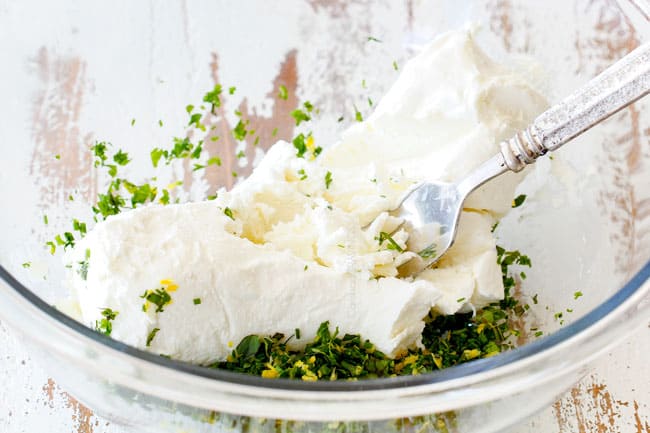 showing how to make cheese log by adding goat cheese to a glass bowl with herbs