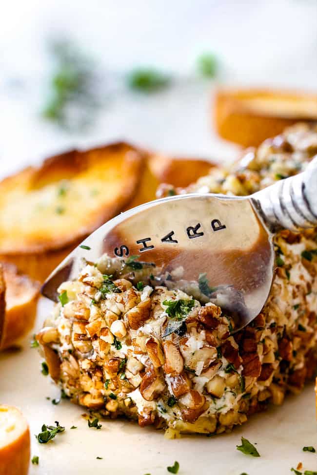 slicing cheese log with garlic, lemon zest, basil, chives, parsley and rolled in pecans with a knife