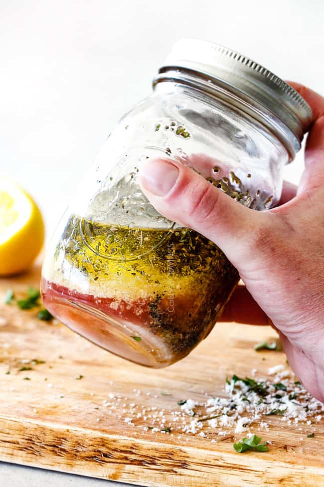 shaking Showing how to make Homemade Italian Dressing by shaking vinegar, oil, garlic, lemon juice, basil, parsley, oregano, salt and pepper in a mason jar