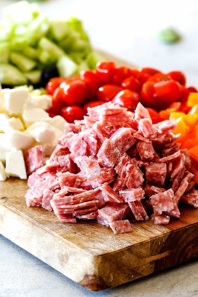 salami, tomatoees, bell peppers, mozzarella, cucumbers on a cutting board for easy Italian Pasta Salad Recipe