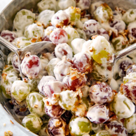 creamy grape salad in a silver bowl with brown sugar and pecans with cream cheese dressing