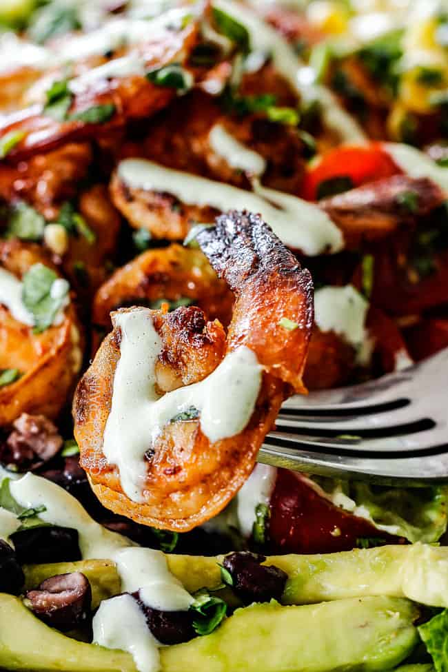 up close of of a fork with a piece of chipotle shrimp from a burrito bowl