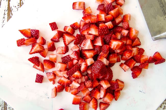 chopping strawberries on a white cuing board for Strawberry Goat Cheese Bruschetta