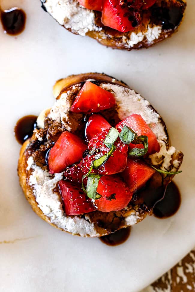 top view of Strawberry Goat Cheese Bruschetta on a white cutting board with Balsamic Reduction
