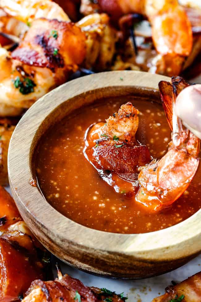 dipping bacon wrapped shrimp in cocktail sauce