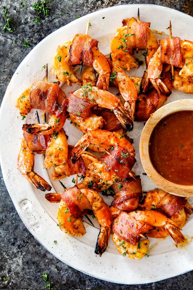 top view of easy bacon wrapped shrimp on a white plate with cocktail sauce