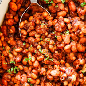 top view of homemade Baked Beans in a blue 9x13 baking dish with green parsley