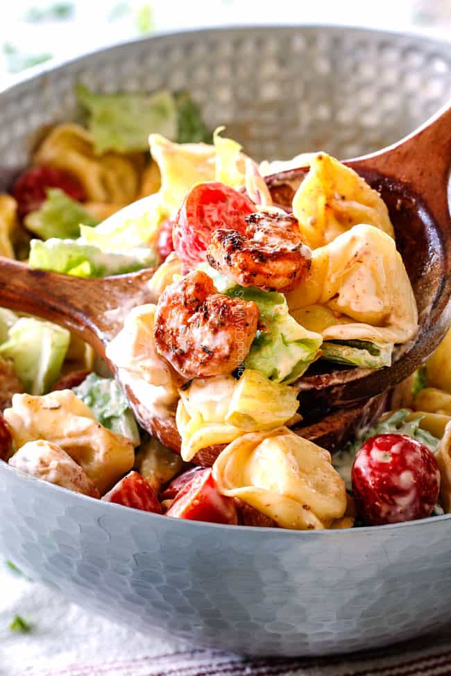 up close of scoop of easy Shrimp Pasta Salad being scooped with wood tongs