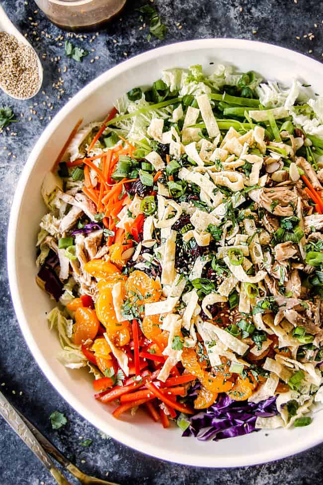 up close top view of crunchy chinese chicken salad with mandarin oranges, napa cabbage, wontons, carrots, snow peas, red bell peppers and sesame ginger dressing