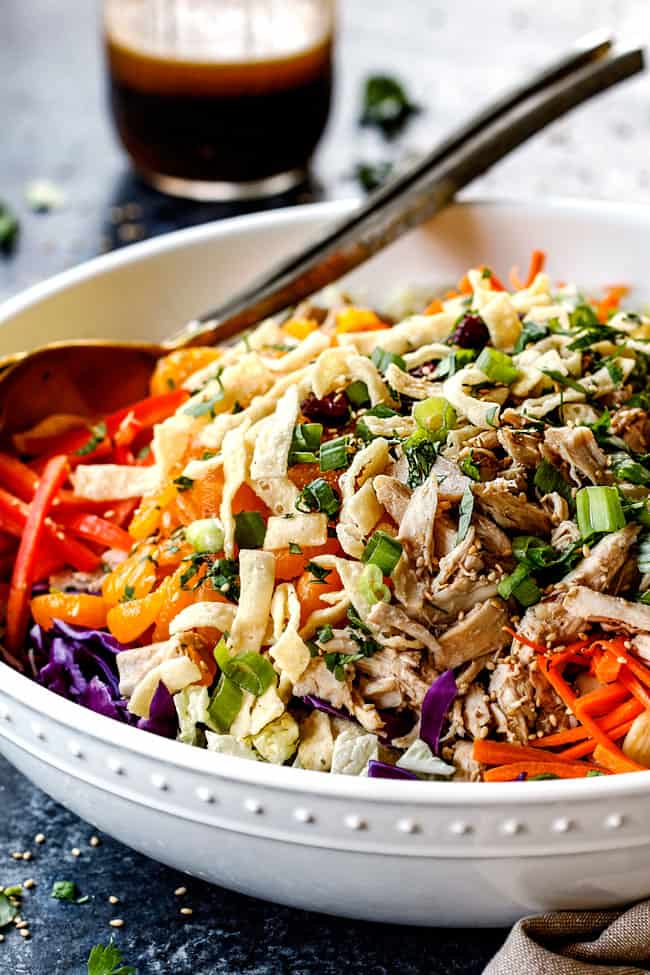 side view of healthy Chinese chicken salad with mandarin oranges, peanuts napa cabbage, wontons, carrots, snow peas, red bell peppers and sesame ginger dressing