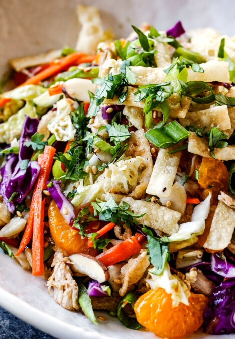 up close side view of top view of crunchy Chinese chicken salad with ramen noodles, Mandarin oranges, peanuts napa cabbage, wontons, carrots, snow peas, red bell peppers all tossed together with sesame dressing
