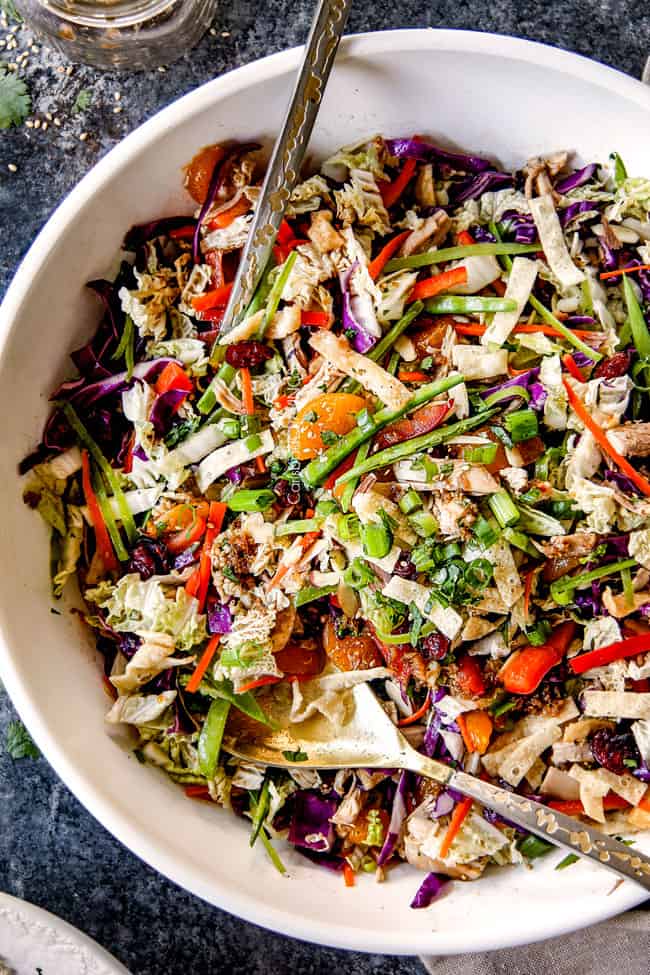 top view of best ever Chinese chicken salad tossed together with mandarin oranges, peanuts napa cabbage, wontons, carrots, snow peas, red bell peppers and sesame ginger dressing