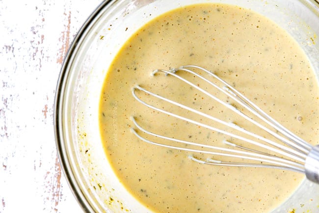 showing how to make Cobb Salad dressing by whisking together dressing ingredients in a glass bowl