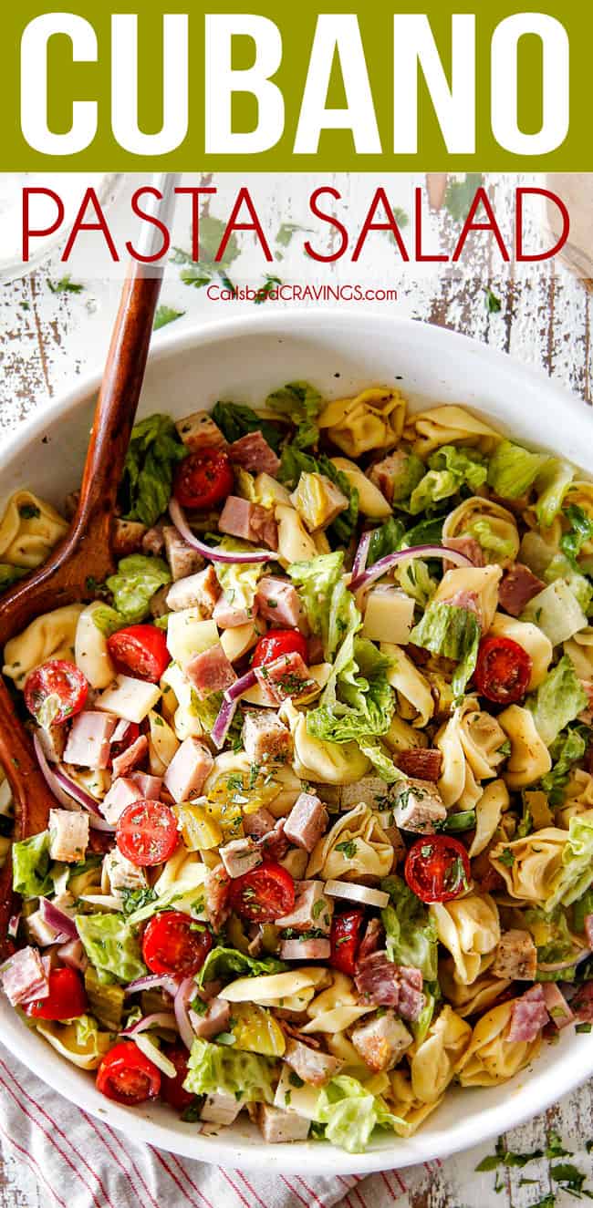 Top view of pasta salad with tongs tossing the pasta salad
