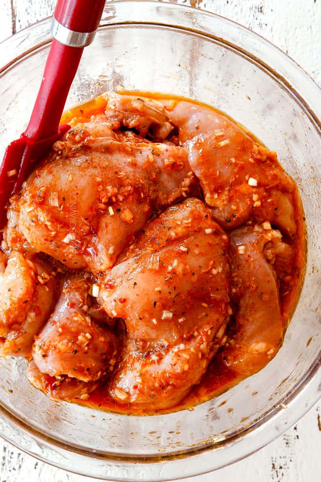 showing how to make lemongrass chicken by marinating chicken in a glass bowl